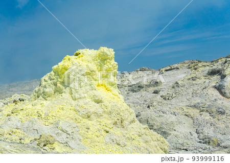 cone of sulfur deposits around a fumarole in a solfataric field against a blue sky cone of sulfur deposits around a fumarole in a solfataric field against a blue sky 93999116