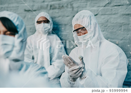 Covid, pandemic and team healthcare workers wearing protective ppe to prevent virus spread at a quarantine site. Concerned first responder wearing a hazmat suit and checking his safety glove Covid, pandemic and team healthcare workers wearing protective ppe to prevent virus spread at a quarantine site. Concerned first responder wearing a hazmat suit and checking his safety glove 93999994