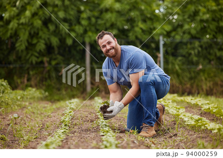 Farmer planting plants or vegetable crops on an organic and sustainable farm and is happy for his seedlings. Excited, joyful and carefree male nature activist who is passionate about sustainability 94000259