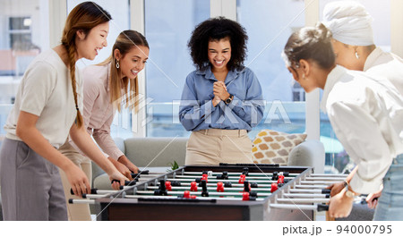 Team building, break and business women playing game in office lounge room having fun and bonding together. Trendy, cool and diversity of creative staff with fun mini table football match activity 94000795