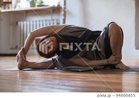 Woman practicing yoga lesson, breathing, doing twisted exercise, working out 94000855