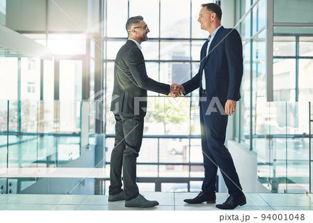 Confident, smiling corporate businessmen exchange handshake in global trust merger meeting together at modern company. Professional executive colleagues in company trade development deal conference 94001048