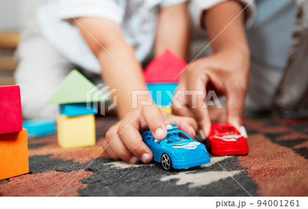 Closeup hands playing with fun toys, cars and building blocks in a home living room. Parent bonding, having fun and enjoying family time with a playful, small and little child during childhood fun Closeup hands playing with fun toys, cars and building blocks in a home living room. Parent bonding, having fun and enjoying family time with a playful, small and little child during childhood fun 94001261