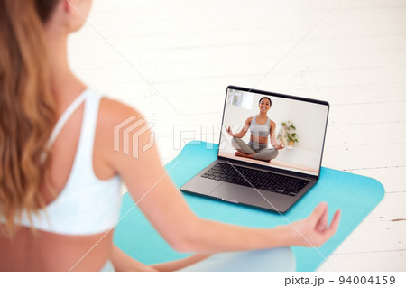 Yoga, meditation and wellness woman watching coach, teacher or professional health and exercise education video or live stream. Girl training and learning how to relax via online classes on a laptop Yoga, meditation and wellness woman watching coach, teacher or professional health and exercise education video or live stream. Girl training and learning how to relax via online classes on a laptop 94004159