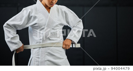 .Beginner, karate and student getting ready for the first day of self defense training against a dark background in a dojo. Determined learner in motivation for fighting lessons in the martial arts. .Beginner, karate and student getting ready for the first day of self defense training against a dark background in a dojo. Determined learner in motivation for fighting lessons in the martial arts. 94004479