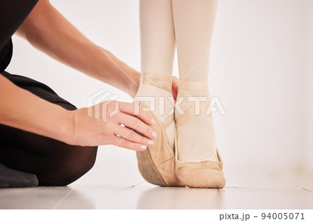 Ballet shoes, feet and learning from her dance coach or instructor about balance on tip toes in hall or studio. Education, motivation and commitment to art teacher and girl ballerina student legs Ballet shoes, feet and learning from her dance coach or instructor about balance on tip toes in hall or studio. Education, motivation and commitment to art teacher and girl ballerina student legs 94005071