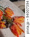 Bright tulips on long green stems on a light background. Ice crystals lie on a round mirror surface. Blurred water droplets on transparent glass. 94007394