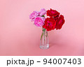 Pale pink and bright red flowers in a glass vase on a pink background. A colorful background will be a great place for your advertising. 94007403
