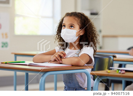 Child or student in class during covid, wearing a mask for hygiene and protection from corona virus flu. Little kindergarten, preschool or elementary school girl sitting in a classroom ready to learn 94007516