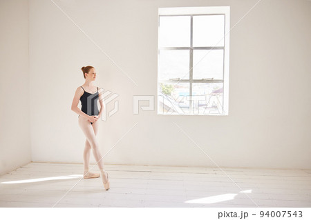 Ballet dancer training or practicing in a dance studio or class for a theater performance. Elegant and serious ballerina or performer dancing and learning contemporary style and performing alone 94007543