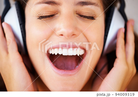 Music, radio and podcast with a woman in headphones listening to and streaming audio while feeling excited, carefree and positive. Happy, freedom and shouting with the face of a young female closeup Music, radio and podcast with a woman in headphones listening to and streaming audio while feeling excited, carefree and positive. Happy, freedom and shouting with the face of a young female closeup 94009319