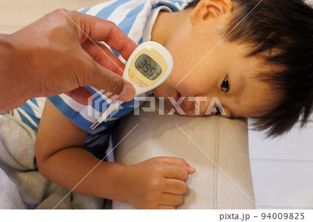 体調不良で寝込む子供と体温計 体調不良で寝込む子供と体温計 94009825