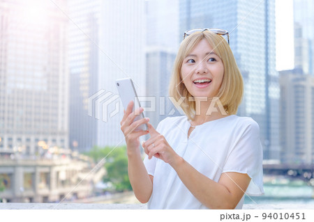 海外でスマートフォンを使う金髪の女性 海外でスマートフォンを使う金髪の女性 94010451