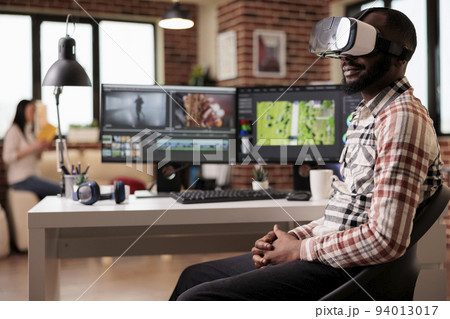 Graphic artist using vr glasses to edit video, working on post production montage with virtual reality headset and creative software on computer. Content creator making film or movie. Graphic artist using vr glasses to edit video, working on post production montage with virtual reality headset and creative software on computer. Content creator making film or movie. 94013017