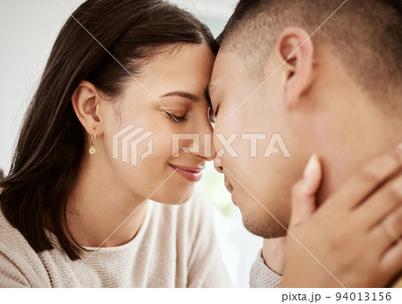 Affectionate, loving and happy couple faces together and relaxing at home enjoying quality time. Loving and romantic lovers bonding and cuddling in the house expressing feelings of love 94013156