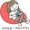 ビーズクッションでスマホを見ながら寛ぐ女性 94014761