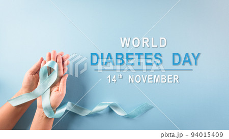 World diabetes day awareness concept. Hand holding blue ribbon, symbolic bow color raising awareness in diabetes day on pastel background,  14 November. 94015409