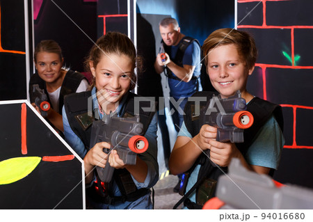 Teenagers with laser guns at other players during laser tag game with parents Teenagers with laser guns at other players during laser tag game with parents 94016680