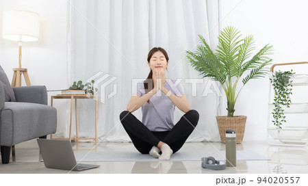 Beautiful Asian woman in sportswear is warming up or doing light exercises in the house with dumbbells and a protein shake or bottle of water and using a laptop at home, Healthy exercise. Beautiful Asian woman in sportswear is warming up or doing light exercises in the house with dumbbells and a protein shake or bottle of water and using a laptop at home, Healthy exercise. 94020557