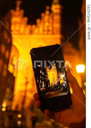 Tourist taking photo on mobile phone of Cityscape of Gdansk with St. Mary Basilica and City Hall at night, Poland. Beautiful architecture of Mariacka street. Social media concept St. Mary's church in Tourist taking photo on mobile phone of Cityscape of Gdansk with St. Mary Basilica and City Hall at night, Poland. Beautiful architecture of Mariacka street. Social media concept St. Mary's church in 94024291