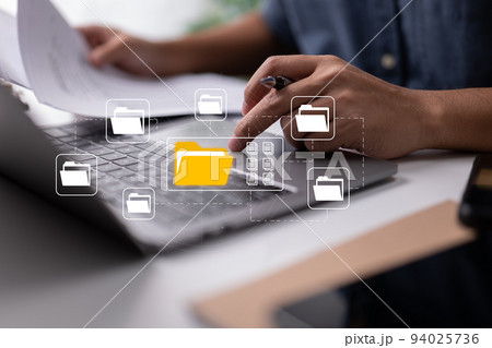 Based on electronic documents, the paperless office concept. While looking at icons for electronic documents on a virtual screen, a businessman types on a laptop keyboard. 94025736