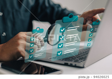 Businessman use magnifying glass with a checklist on clipboard paper. Successfully complete business assignments. 94026025