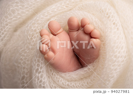 Soft feet of a newborn in a white woolen blanket. Close-up of toes, heels and feet of a newborn baby. The tiny foot of a newborn. Studio Macro photography. Baby feet covered with isolated background.  94027981