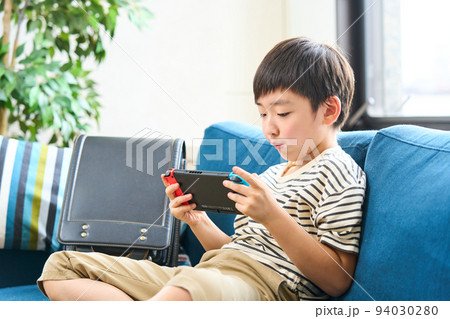 ソファーに座りゲームをする小学生　 94030280