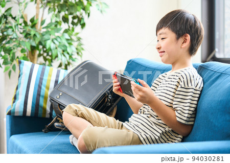 ソファーに座りゲームをする小学生　 94030281