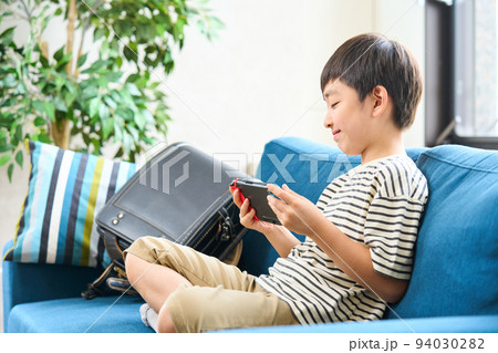 ソファーに座りゲームをする小学生　 94030282