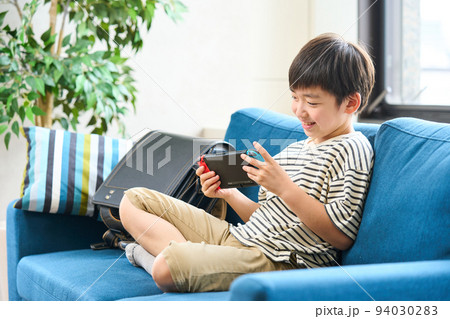 ソファーに座りゲームをする小学生　 94030283