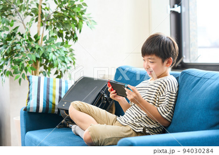 ソファーに座りゲームをする小学生　 94030284