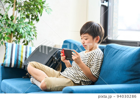 ソファーに座りゲームをする小学生　 94030286