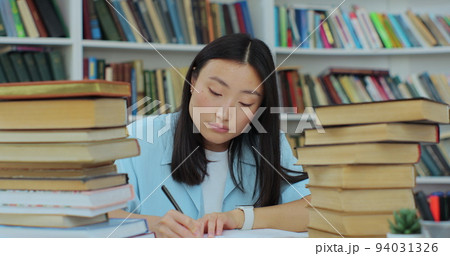 Student collecting information from different books, Beautiful asian girl in blue shirt gathering data for the paper. Self education concept. 94031326