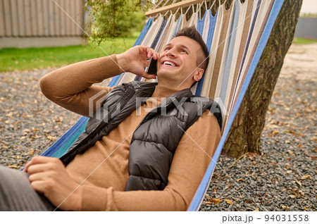 Joyous vacationer having a phone conversation outdoors Joyous vacationer having a phone conversation outdoors 94031558