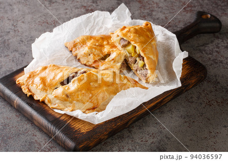 English pies Cornish pasties stuffed with beef, potatoes and swede close-up on paper. horizontal 94036597