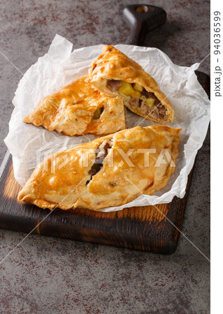 Traditional Cornish pasty filled with meat potato swede and carrot closeup on the paper. Vertical 94036599