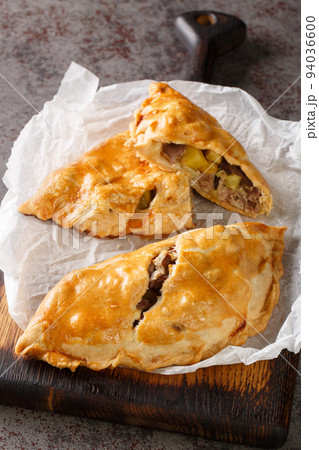 Freshly baked homemade Cornish pasties closeup on the wooden board. Vertical 94036600