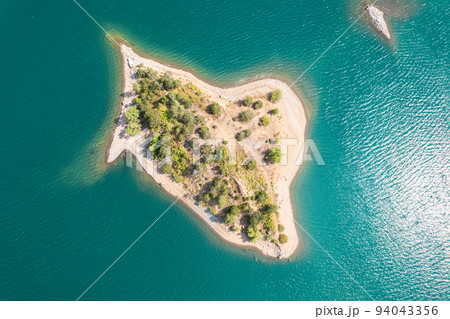 Small uninhabited, desert sand island with many trees in the middle of sea. Drone view, aerial view, top view Small uninhabited, desert sand island with many trees in the middle of sea. Drone view, aerial view, top view 94043356