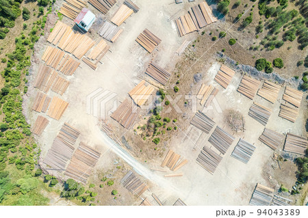 Aerial view of sawmill with timber, chopped  a lot of pine tree wood logs. Top, drone view 94043389