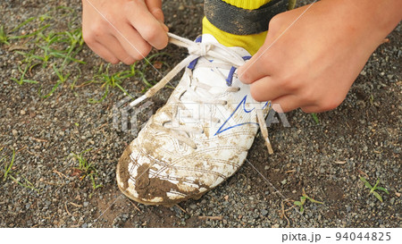 サッカーシューズの紐を結ぶ少年 94044825