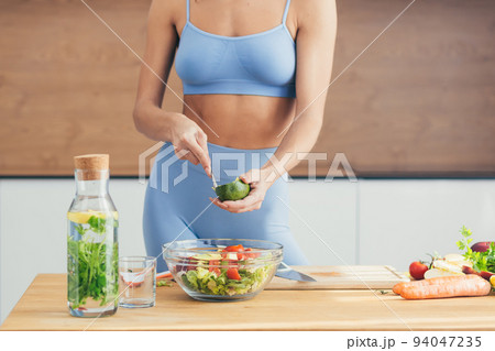 Close up photo, body part, hands of young fitness woman making salad with fresh vegetables and fresh detox eap in kitchen at home Close up photo, body part, hands of young fitness woman making salad with fresh vegetables and fresh detox eap in kitchen at home 94047235