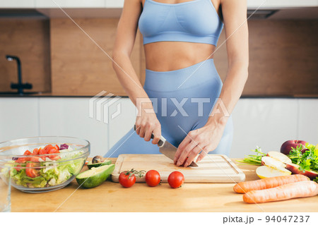 Close up photo, body part, hands of young fitness woman cutting fresh vegetables on kitchen salad at home Close up photo, body part, hands of young fitness woman cutting fresh vegetables on kitchen salad at home 94047237