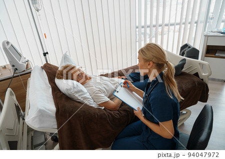 Professional doctor in uniform examines the patient during a visit to hospital ward 94047972