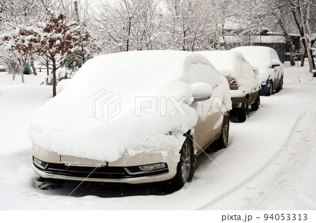 Fragment of the car under a layer of snow after a heavy snowfall. The body of the car is covered with white snow 94053313