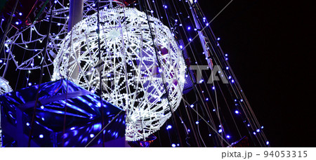 Fragment of the New Year tree. A lot of round lights of blue color are located on a conical frame 94053315
