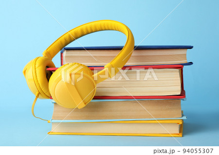 Books and modern headphones on light blue background Books and modern headphones on light blue background 94055307