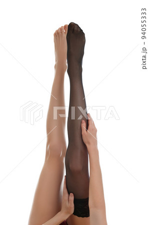 Young woman putting on stocking against white background, closeup Young woman putting on stocking against white background, closeup 94055333