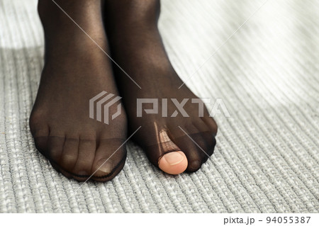 Woman wearing torn tights at home, closeup Woman wearing torn tights at home, closeup 94055387