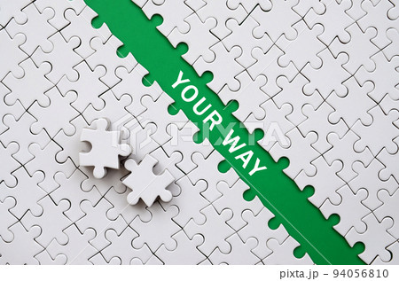 Your way. The green path is laid on the platform of a white folded jigsaw puzzle. The missing elements of the puzzle are stacked nearby Your way. The green path is laid on the platform of a white folded jigsaw puzzle. The missing elements of the puzzle are stacked nearby 94056810